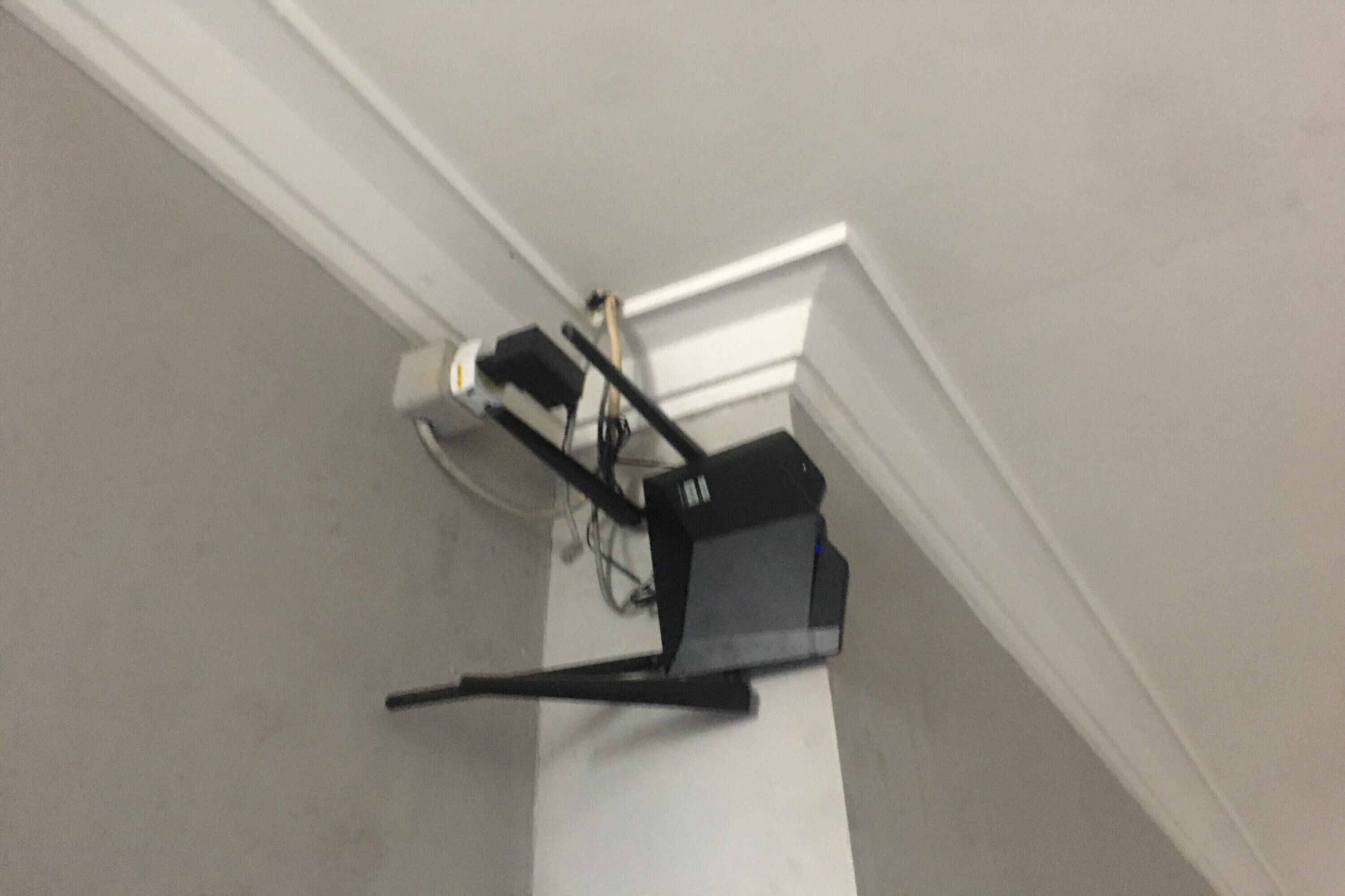 Esquina de una habitación con una pared blanca y un objeto negro fijado a ella.