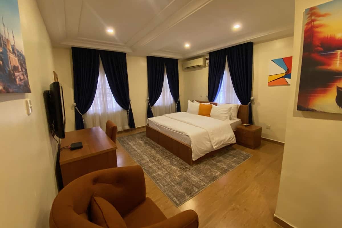 A hotel room with a bed, a desk, a chair, and a TV.