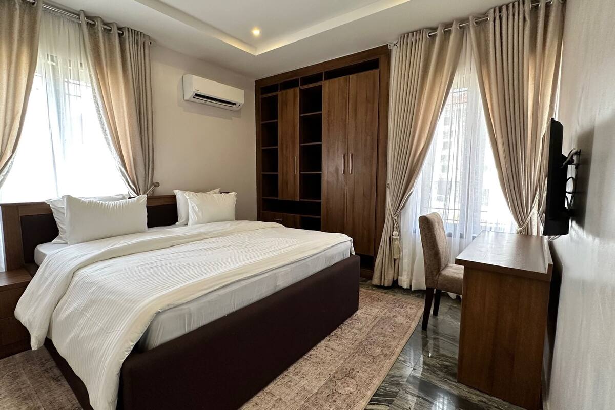 Une chambre spacieuse avec un grand lit, une armoire en bois et un bureau avec une chaise.