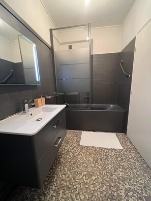 Bathroom features a large mirror, sink, and glass shower enclosure.