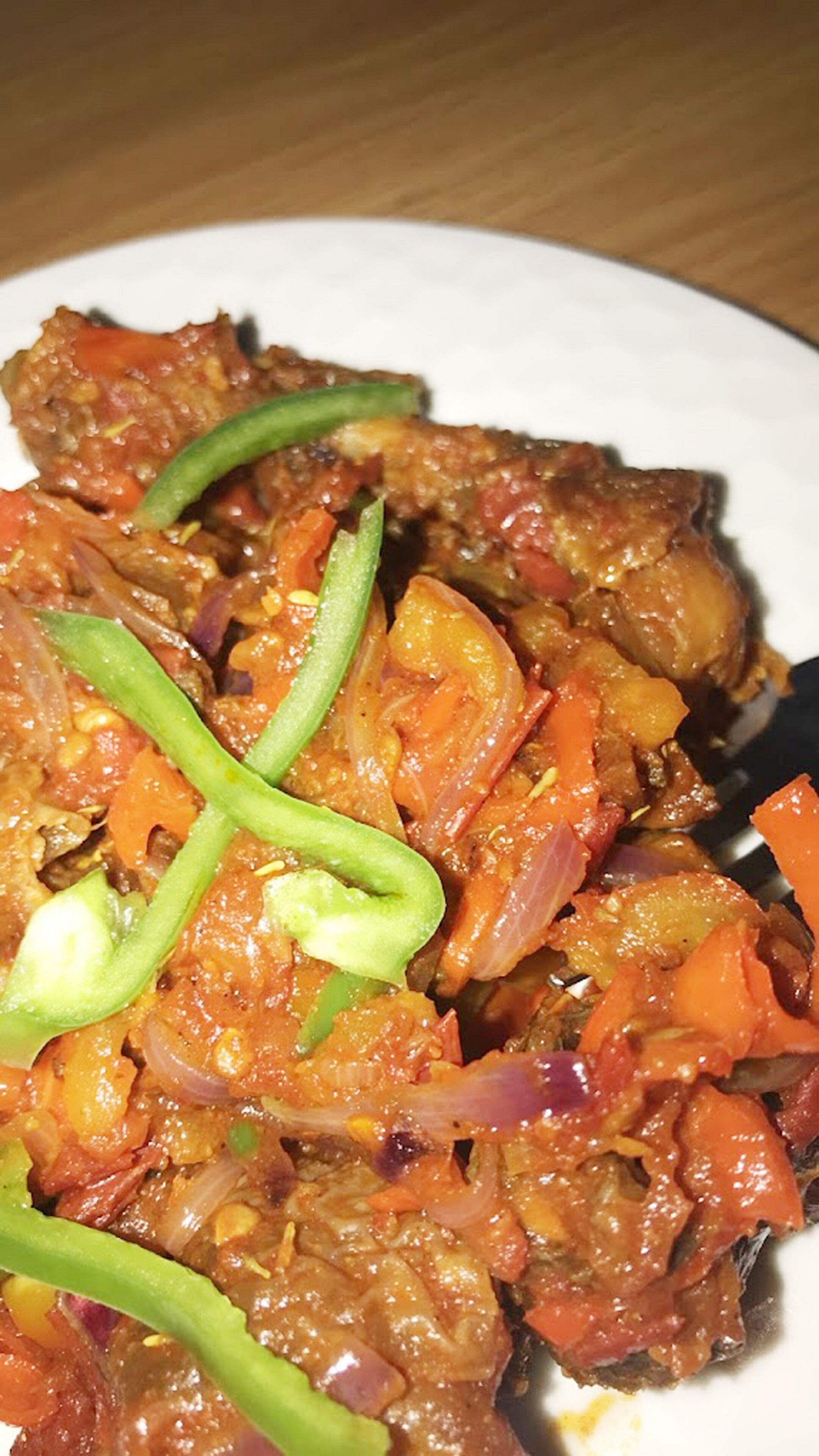 Primer plano de un plato con carne, verduras y salsa.