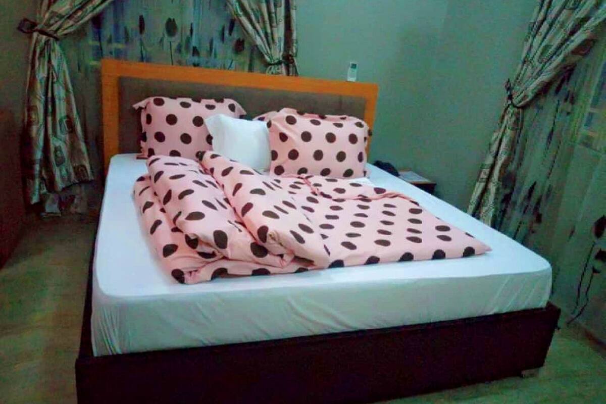 A bed with a polka dot blanket and matching pillows, a wooden headboard, and a white mattress.