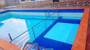 A swimming pool with blue tiles and a metal ladder. - VICPEALIA HOTEL LTD (Uyo)