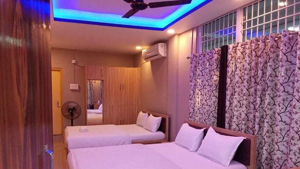A hotel room with two beds, a ceiling fan, and a window with curtains. - 3 Star Lodge (North Lakhimpur)
