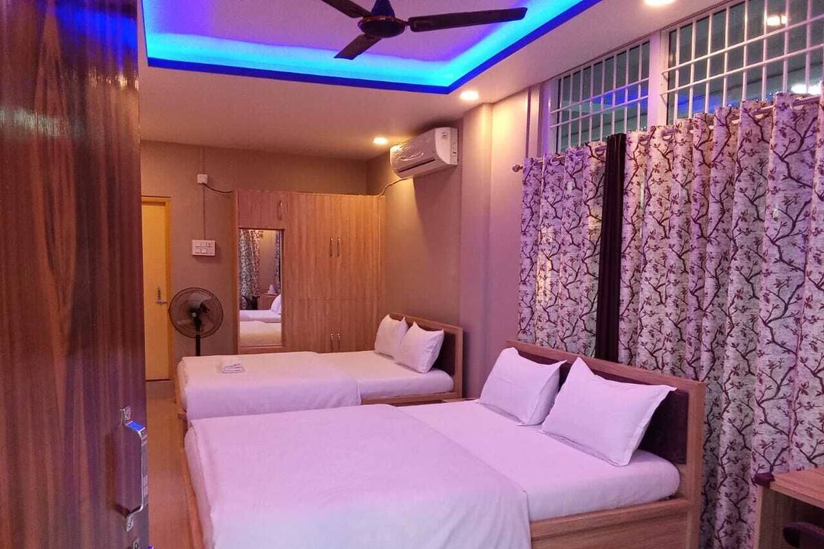 A hotel room with two beds, a ceiling fan, and a window with curtains.