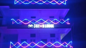 A building with a neon sign reading "3ST LODGE" and a store named "momomia" below it. - 3 Star Lodge (North Lakhimpur)