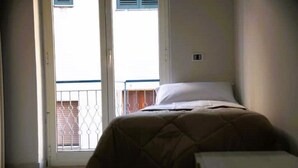 Una habitación con cama, una mesita y vistas a un balcón con barandilla.