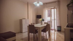 Un espacio habitable compacto con comedor, kitchenette y televisor.
