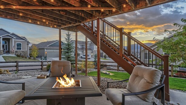 Un patio al aire libre con una chimenea, asientos y vistas a un barrio residencial.