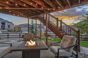 An outdoor patio with a fire feature, seating, and a view of a residential neighborhood. - Mountainview Marvel (Monument)