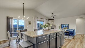 Una cocina moderna con una isla grande, muebles oscuros y una zona de comedor con un sofá azul.