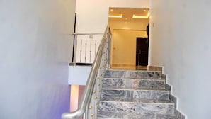 A marble staircase with a metal railing leading to a room with a dark door. - STAR SAPPHIRE LUXURY HOTELS LTD (Uyo)