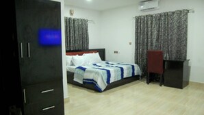 A bedroom with a bed, a desk, and a wardrobe. - STAR SAPPHIRE LUXURY HOTELS LTD (Uyo)