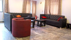 A living room with two sofas, a red ottoman, and a marble floor. - STAR SAPPHIRE LUXURY HOTELS LTD (Uyo)