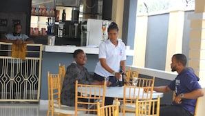 A group of people seated at a table in a restaurant with a counter and various food items in the background. - STAR SAPPHIRE LUXURY HOTELS LTD (Uyo)