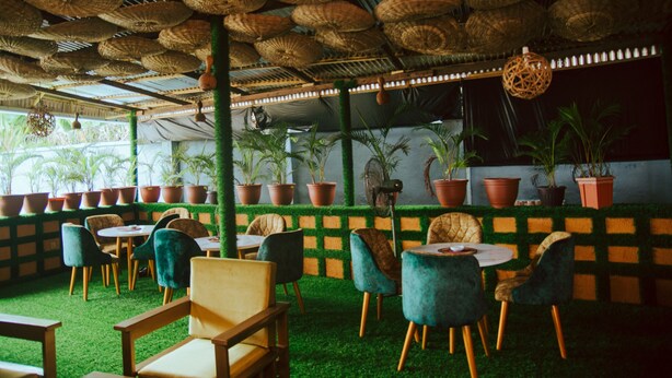 An indoor seating area with round tables, chairs, and potted plants.