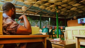 A person seated at a table in a restaurant with a ceiling covered in woven baskets.