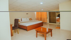A hotel room with a large bed, a wooden nightstand, a chair, and a small wooden table.
