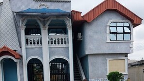 A two-story building with a symmetrical facade, a central entrance with a staircase, and a paved courtyard. - Haffy Executive Hotels and Suite (Uyo)