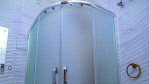 A glass-enclosed shower with a curved design, a white tiled wall, and a visible plumbing fixture. - Haffy Executive Hotels and Suite (Uyo)