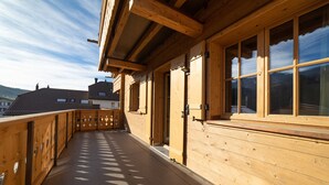 A wooden balcony with a view of neighboring buildings and a clear sky.