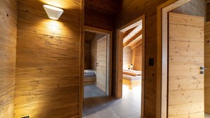A wooden interior with a bed, a nightstand, and a wall-mounted light fixture.