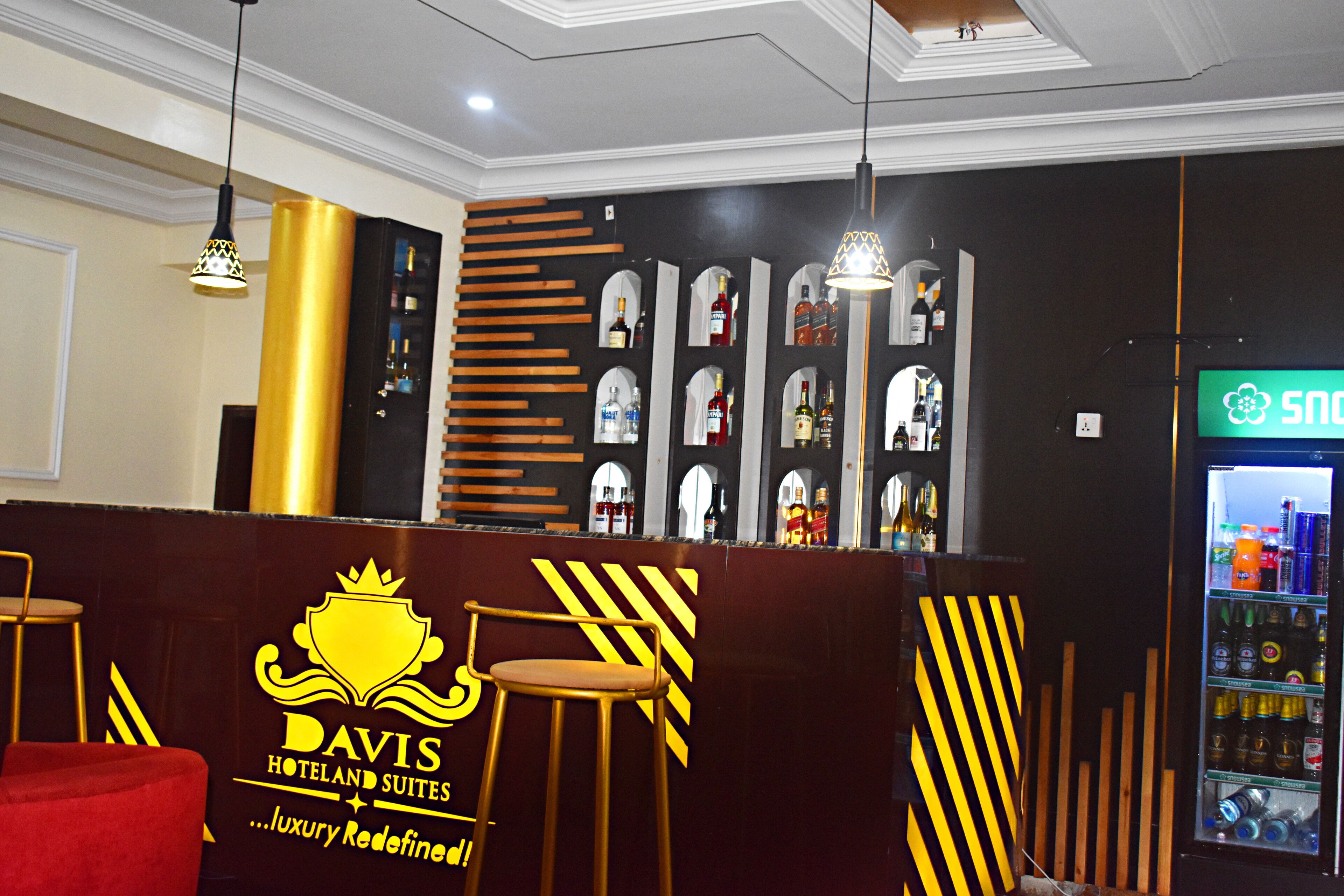 A hotel reception area with a bar counter, stools, and a minibar.