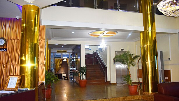 A lobby with a reception desk, a staircase, and potted plants. - DAVIS HOTEL & SUITES (Port Harcourt)