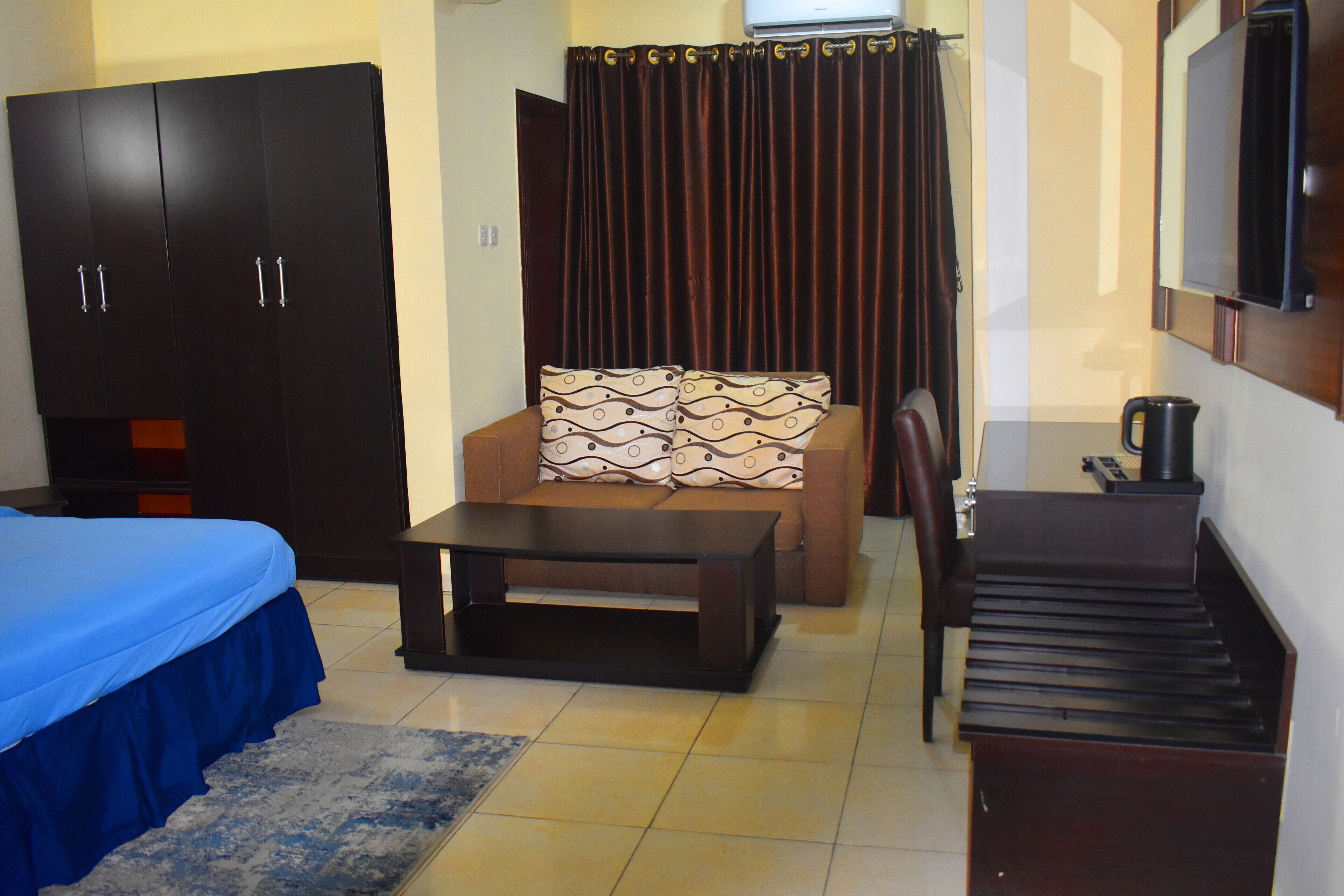 Une chambre d’hôtel comprenant un lit, un canapé, une table basse, une télévision et une armoire.