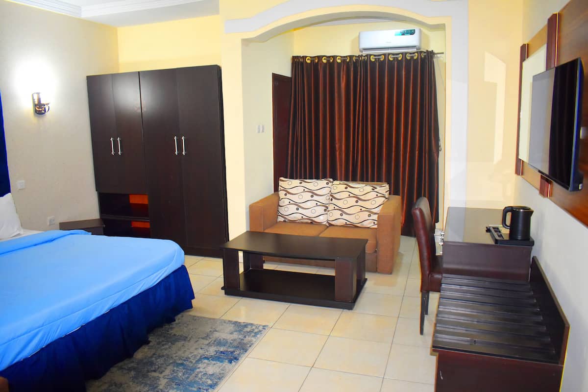 A hotel room with a bed, a sofa, a coffee table, a TV, and a wardrobe.