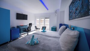 A modern hotel room with a large bed, a desk with a computer, a chair, and a painting on the wall. - Boutique Hotel& Relax Sagittarius (Kyustendil)