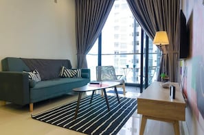 A modern living room with a sofa, a coffee table, a small table, a lamp, and a TV mounted on the wall.