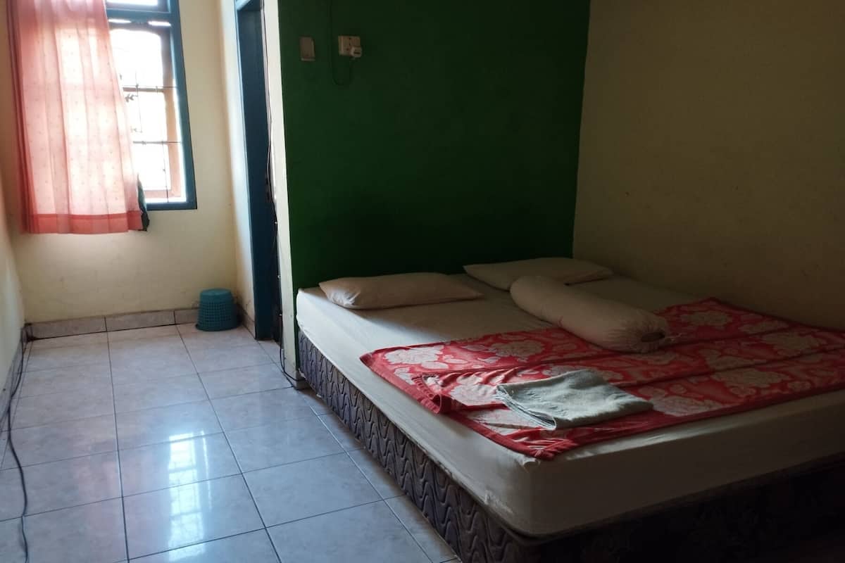 Ein Zimmer mit einem Bett, einem Vorhangfenster, einer grünen Wand und einem Fliesenboden.