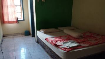 Una habitación con una cama, un ventanal con cortinas, una pared verde y un piso de baldosas.