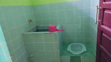 Um banheiro pequeno com vaso sanitário, um balde rosa e uma porta.