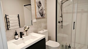 Ein modernes Badezimmer mit einer gläsernen Dusche, einem weißen Waschbecken und einer Toilette.