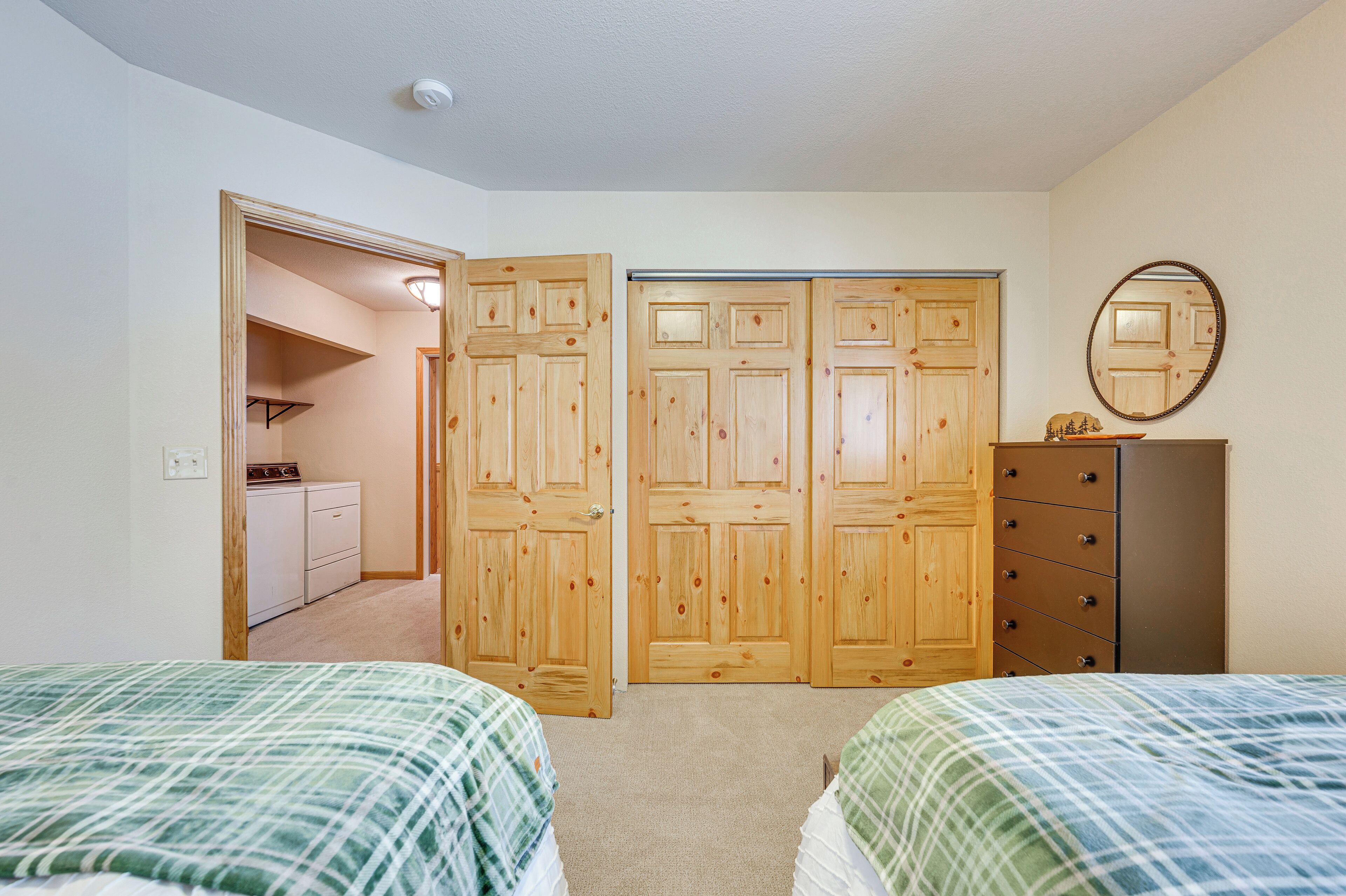Une chambre avec deux lits, une commode, un miroir et un placard à trois portes.