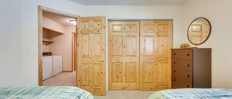 Une chambre avec deux lits, une commode, un miroir et un placard à trois portes.