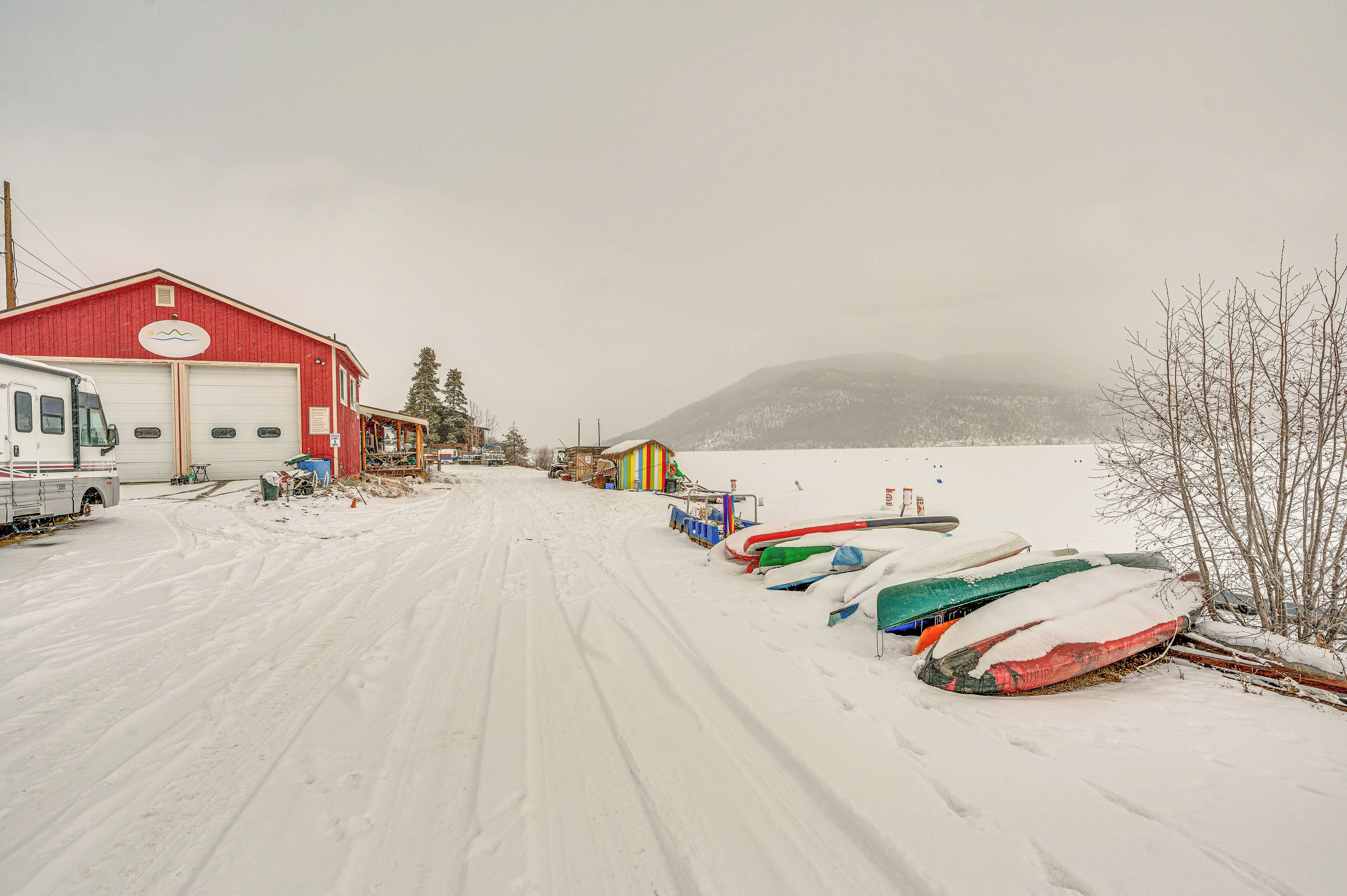 A snow-covered road with a red building and a truck parked on the left.