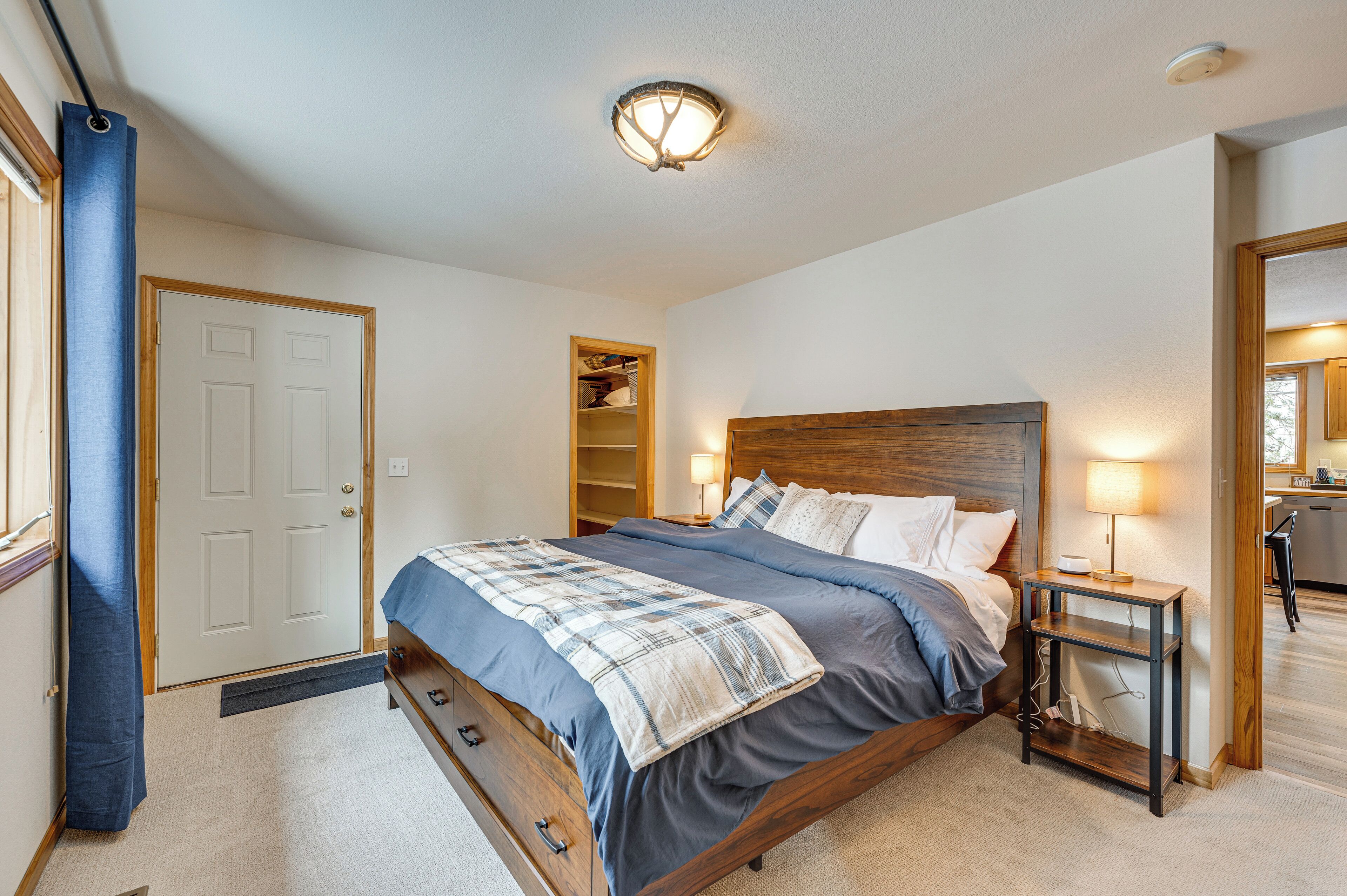 A bedroom with a bed, bedside tables, a nightstand, a wardrobe, and a ceiling light fixture.