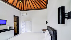 A hotel room with a large bed, a flat-screen TV, a heater, and a ceiling with a wooden design. - Collection O Legian Near Bimc Hospital Nusa Uda Formerly Anna Kuta Inn (Kuta)