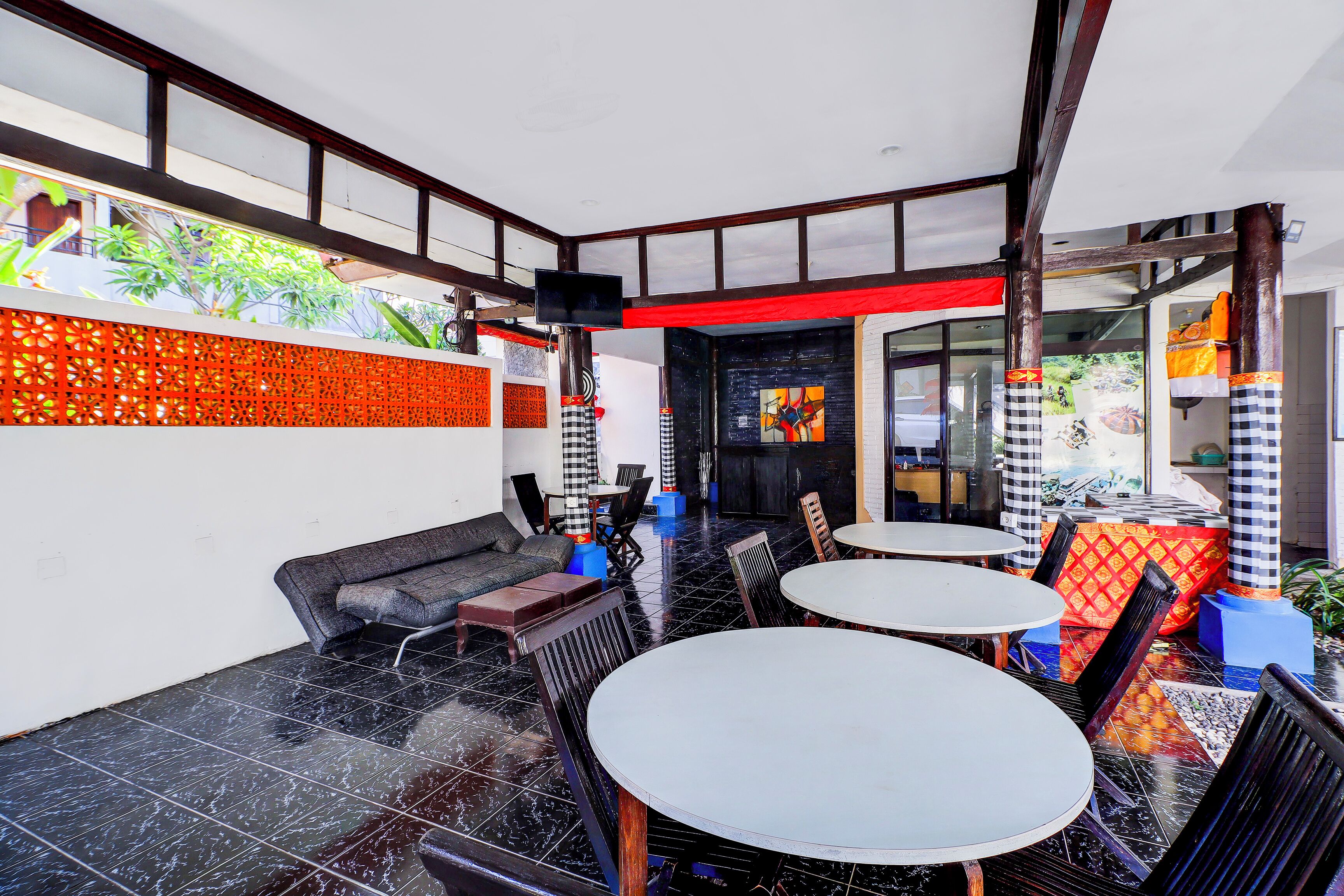 A modern indoor space with black-tiled floors, a black and white checkered sofa, and round tables.