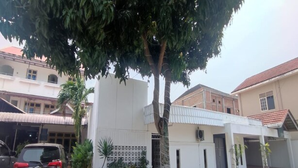 A building with a white facade, a covered entrance, and a parked car.