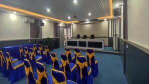 A conference room with rows of chairs covered in blue and yellow fabric, a podium, and a blue carpeted floor.