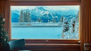 Une pièce dotée d’une grande fenêtre donnant sur des montagnes enneigées et un lac.