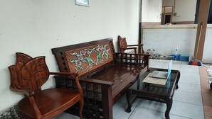 Een houten bank met ingewikkelde houtsnijwerken, een bijpassende houten stoel en een glazen bijzettafeltje.