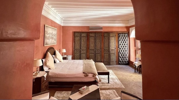 A bedroom with a large bed, a nightstand, a bench, and a wardrobe. - Riad Sassa Finda (Marrakech)