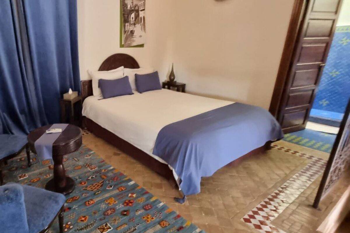 A bedroom with a bed, a chair, a small table, and a patterned rug.