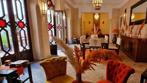 A hotel lobby with a dining area, a reception desk, and a large window with decorative glass. - Riad Sassa Finda (Marrakech)