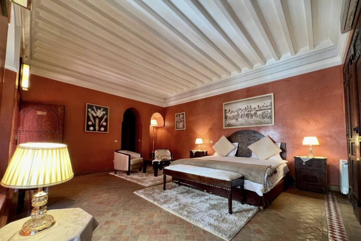 A bedroom with a large bed, two bedside tables, a chair, and a lamp.